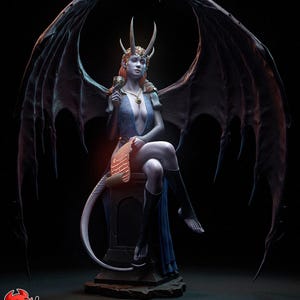 Può includere: Scultura dettagliata di una demone femminile con grandi ali scure, corna e una lunga coda. Indossa un abito blu e tiene in mano un calice. La figura è seduta su un piedistallo di pietra su sfondo nero.
