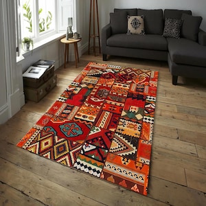 May include: A rectangular, patchwork-style rug with a vibrant mix of colors and patterns. The rug features a predominantly red background with geometric and tribal-inspired designs in orange, blue, and white. It is placed on a wooden floor in a living room setting.