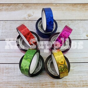 May include: Assortment of six rolls of iridescent washi tape with a heart pattern. The tape is in the colors blue, red, green, gold, pink, and purple.
