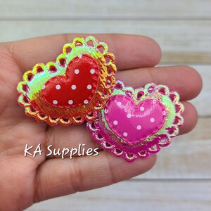 May include: Two iridescent heart-shaped embellishments with white polka dots. The hearts are layered with a scalloped edge.