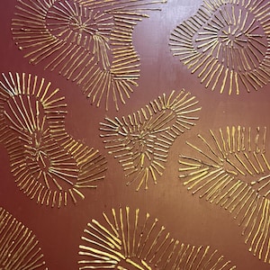 Puede incluir: Una pieza de arte mural cuadrada con un fondo granate oscuro y cinco patrones texturizados en relieve de color dorado. Cada patrón consiste en líneas radiantes que emanan de un punto central, creando un efecto radial orgánico.