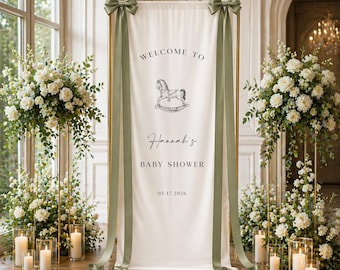 May include: A baby shower banner with the text "WELCOME TO Hannah's BABY SHOWER 05.17.2026" and a rocking horse illustration. The banner is cream-colored with olive green ribbons and bows. The scene is decorated with white flowers and candles.