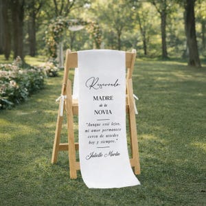 May include: A wooden chair with a white fabric banner draped over it. The banner has the word "Reservado" at the top, followed by text in Spanish. The chair is set outdoors on a grassy area.