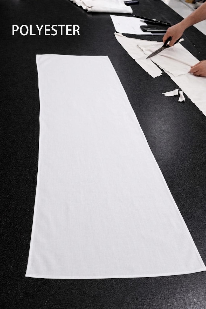 Puede incluir: Una gran tela blanca de poli&eacute;ster colocada sobre una superficie negra. La palabra "POLYESTER" est&aacute; impresa en blanco en la esquina superior izquierda. Una persona est&aacute; cortando tela con tijeras en el fondo.
