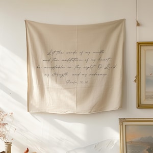 May include: Beige fabric wall hanging with black script text. The text reads "Let the words of my mouth...be acceptable in thy sight. O Lord. my strength. and my redeemer. Psalm 19:14."