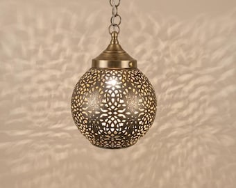 Może przedstawiać: Sferyczna lampa wisząca z wykończeniem w kolorze antycznego mosiądzu, posiadająca skomplikowane, wycinane laserowo geometryczne wzory, przez które przenika światło. Lampa zawieszona jest na pasującym metalowym łańcuchu i emituje ciepły blask.