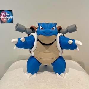 Puede incluir: Una figura de Blastoise azul y beige con dos cañones grises en la espalda, garras blancas y un caparazón marrón. La figura presenta una expresión facial severa y está en una pose frontal. Un pequeño logotipo cuadrado dice Perfect PrintingAU.