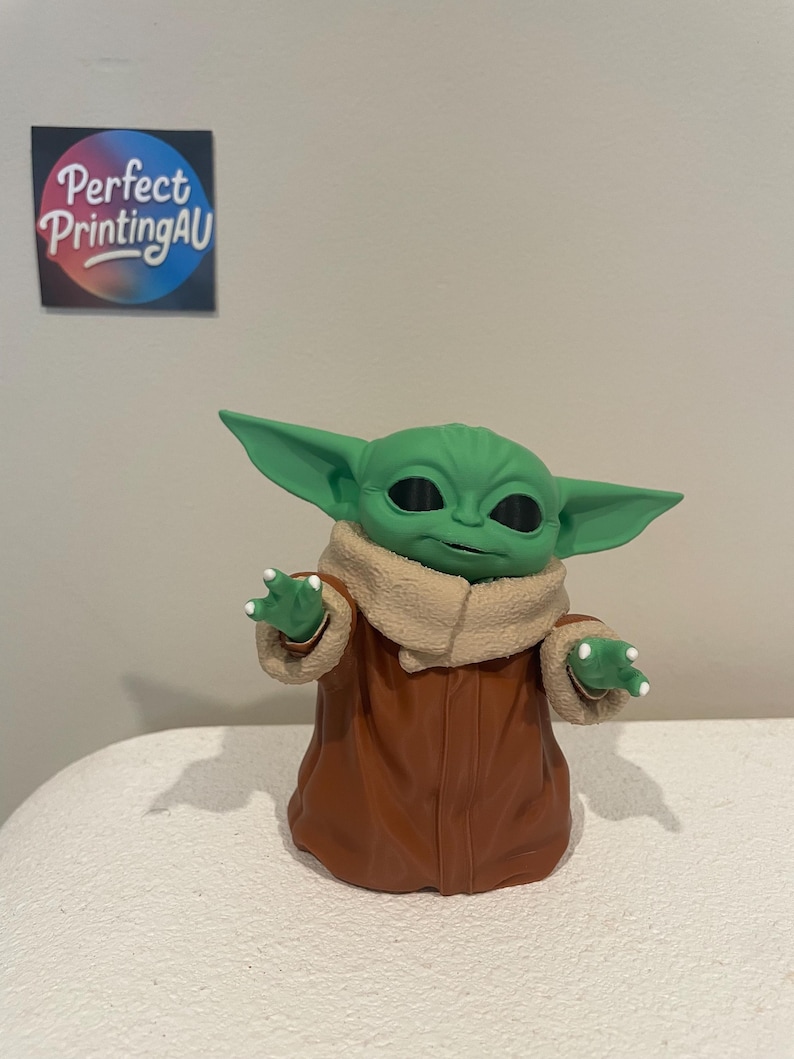 May include: A green figurine of a character with large ears, wearing a brown coat with a tan collar. The figurine has black eyes and small white claws. The text "Perfect PrintingAU" is on a sticker in the background.