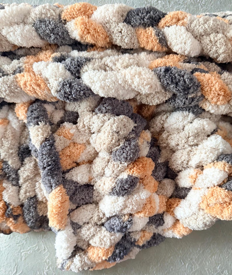Detailed view of Toasted Birch chunky knit blanket with thick braided texture in warm neutral tones of ivory, tan, and charcoal gray.