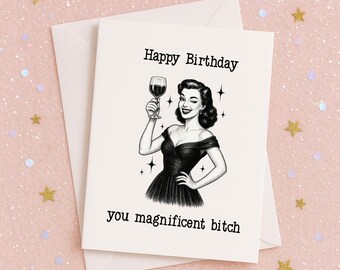 May include: A greeting card with a vintage illustration of a woman holding a wine glass, with the text "Happy Birthday" and "you magnificent bitch". The card is on a white envelope, with a pink background and gold star confetti.
