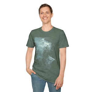 Könnte beinhalten: Grünes T-Shirt mit Rundhalsausschnitt und hellblauem Rauchdesign auf der Vorderseite. Das Shirt besteht aus einem weichen Material und eignet sich für Freizeitkleidung. Das Model trägt blaue Jeans.