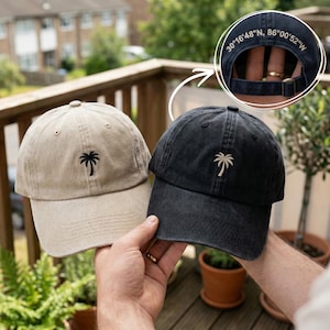 May include: Two baseball caps, one tan and one black, each with a palm tree logo embroidered on the front. The black cap has the coordinates "30°16'48"N, 86°00'52"W" embroidered on the back.