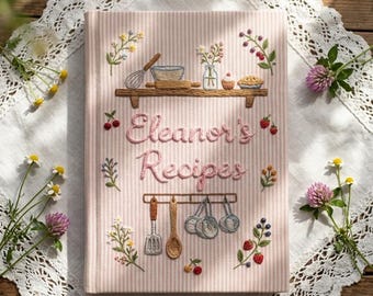 May include: A light pink and white striped fabric-covered recipe book with embroidered kitchen motifs. The cover features the text "Eleanor's Recipes" in pink thread, a shelf with a whisk and bowl, and hanging kitchen utensils below.