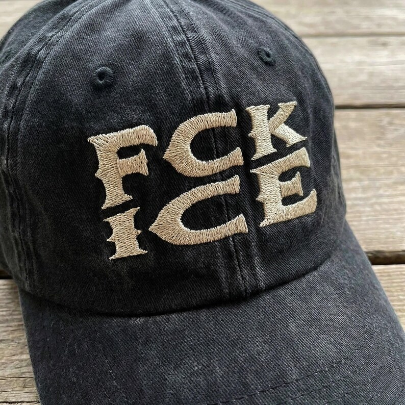 May include: Black baseball cap with the embroidered text "FCK ICE" in a tan color. The hat is made of a soft, worn fabric and has a curved brim. The hat is a casual accessory.