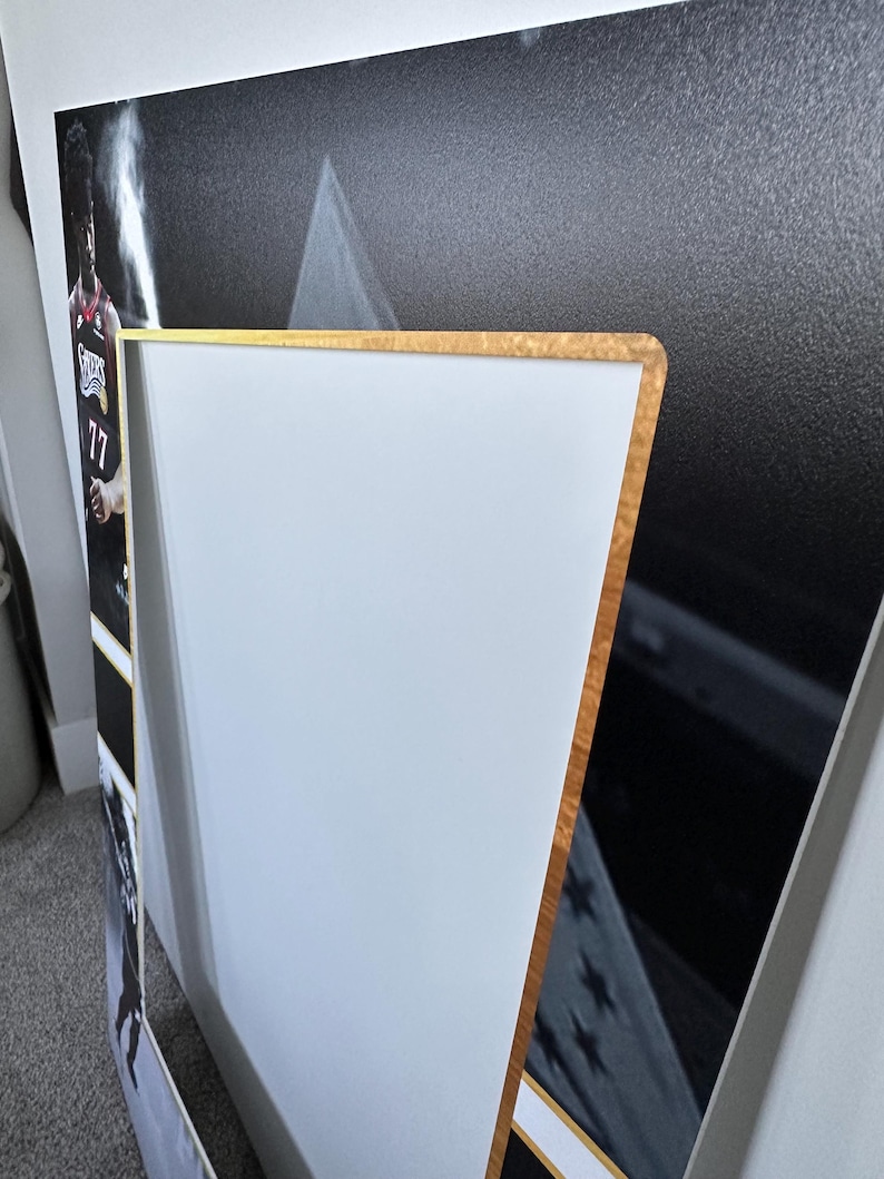 May include: A framed sports print featuring a basketball player in a red and black jersey with the number 17. The frame has a gold-colored edge and a white border. The background is black and white.