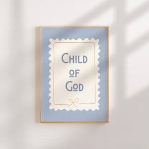 Könnte beinhalten: Ein gerahmter Kunstdruck mit den Worten "CHILD OF GOD" in Marineblau auf cremefarbenem Hintergrund. Der Druck hat einen hellblauen Rand und einen Holzrahmen. Am unteren Rand des cremefarbenen Hintergrunds befindet sich eine kleine Schleife.