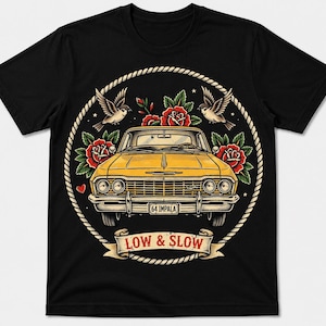 以下が含まれることがあります： ロープの円の中に黄色い1964年型インパラの車が描かれた黒いTシャツ。デザインには赤いバラ、2羽の鳥、そして下部にLOW & SLOWという文字が書かれたバナーが含まれています。ナンバープレートには64 IMPALAと記されています。