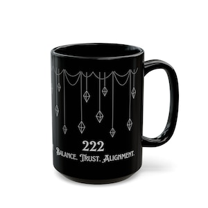 May include: Black ceramic mug with white geometric design and the number 222. The mug features the words "Balance. Trust. Alignment." in white. The mug has a large handle and is suitable for hot or cold beverages.