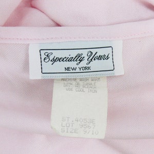 May include: Close-up of a light pink garment with a tag that reads "Especially Yours NEW YORK." The tag also includes washing instructions and size information. The garment is a soft, possibly knit, material.