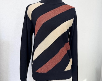 May include: A black turtleneck sweater with diagonal stripes in cream and rust colors. The long-sleeved sweater is displayed on a mannequin. The sweater has a ribbed collar, cuffs, and hem.