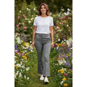 Puede incluir: Una camiseta blanca de manga corta con cuello redondo combinada con pantalones de cuadros grises de cintura alta y un ligero vuelo en el bajo. Los pantalones presentan un estampado de cuadros clásico en tonos grises y negros, con zapatillas blancas.