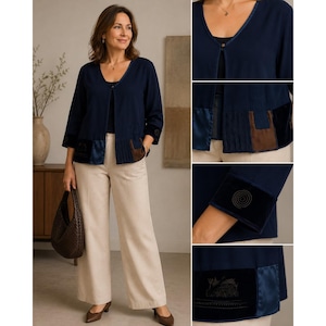 Puede incluir: Una chaqueta azul marino abierta con mangas tres cuartos, cuello en V, cierre de un solo botón y un dobladillo con paneles de terciopelo en contraste marrón y negro, combinada con pantalones beige de pierna ancha y un bolso marrón oscuro.