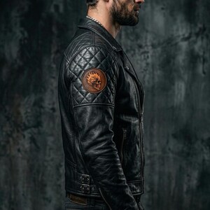 May include: Black leather jacket with quilted shoulder detail and a skull patch. The jacket features a classic biker style with a zip closure and a fitted silhouette. The model is wearing a black beanie and dark jeans.