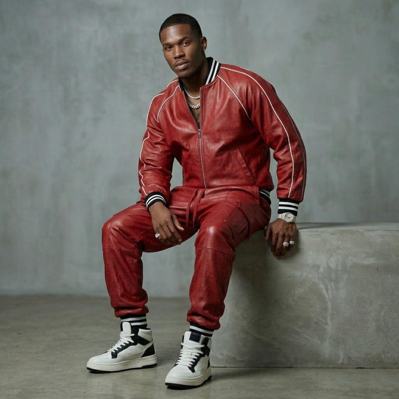 Puede incluir: Un conjunto de chaqueta bomber y pantal&oacute;n de cuero rojo. La chaqueta tiene rayas blancas y pu&ntilde;os a rayas blancas y negras. El pantal&oacute;n tiene bolsillos. El conjunto se combina con zapatillas altas blancas y negras.