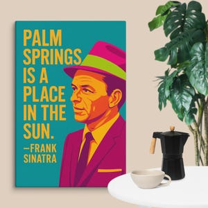 Pode incluir: Impressão em tela em estilo pop art com Frank Sinatra em um terno e chapéu magenta com uma faixa verde. O texto diz "Palm Springs is a place in the sun." e é assinado por Frank Sinatra.