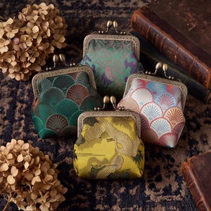 May include: Four small coin purses with antique brass-toned metal kiss-lock frames. The purses feature various fabric patterns including green and purple swirls, dark green fan shapes, multi-colored fan motifs, and a yellow crane design.