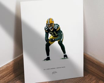 May include: A print featuring a football player in a green and yellow uniform, with the number 21. The player is in a defensive stance. The print includes the text "#21 CHARLES WOODSON // GREEN BAY PACKERS" and a signature.