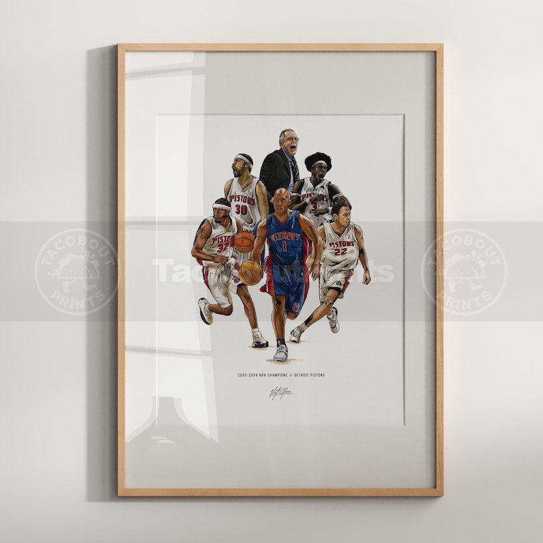 May include: A framed art print featuring a group of basketball players in white and blue Detroit Pistons uniforms, with a coach in a suit. The text reads 2003-2004 NBA CHAMPIONS DETROIT PISTONS. The players are shown in action with basketballs.