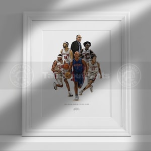 May include: A framed art print featuring a detailed illustration of the 2004 Detroit Pistons basketball team and coach in action. The players wear white and blue uniforms, with text at the bottom reading 2003-2004 NBA CHAMPIONS // DETROIT PISTONS.