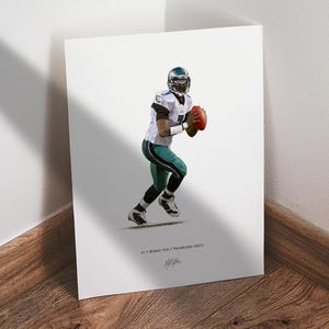 May include: A print featuring an illustration of a football player in a white and green uniform, holding a football. The print includes the text "BY // MICHAEL VICK // PHILADELPHIA EAGLES" and a signature.
