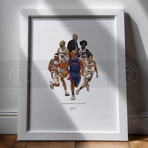 May include: A framed art print featuring a detailed illustration of the 2003-2004 Detroit Pistons basketball team, including players in white and blue uniforms, a coach, and basketballs, with the text 2003-2004 NBA CHAMPIONS // DETROIT PISTONS.