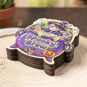 May include: A stack of wooden coasters with a Halloween theme. Each coaster features a cartoon illustration of a witch stirring a bubbling cauldron with the text "Spooky Brew". Additional graphics include a bat, pumpkin, and ghosts.