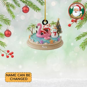 May include: A Christmas ornament featuring Santa Claus on a pink flamingo float in a pool, with a snowman and Christmas tree. The ornament has a beach theme with palm trees, starfish, and seashells. The text "Name" is visible on the base.