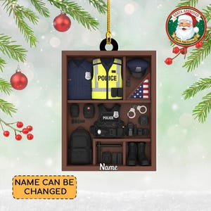 May include: A wooden Christmas ornament shaped like a police officer's equipment display. The ornament features a uniform, vest, hat, handcuffs, and other accessories. The text "Name" is at the bottom, and "Name Can Be Changed" is on a yellow rectangle.