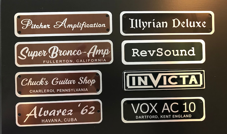 Puede incluir: Ocho placas met&aacute;licas con borde plateado y letras blancas. Las placas muestran los nombres de marcas y fabricantes de amplificadores de guitarra, incluyendo "Pitcher Amplification", "Illyrian Deluxe", "Super Bronco-Amp", "RevSound", "Chuck's Guitar Shop", "INVICTA", "Alvarez '62" y "VOX AC 10".