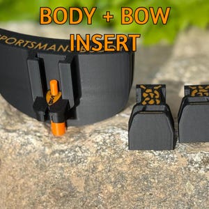 Puede incluir: Inserto de arco negro con detalles en naranja. El texto "BODY + BOW INSERT" se muestra en naranja. La palabra "SPORTSMAN" es visible en el inserto negro. El inserto está sobre una superficie de piedra.