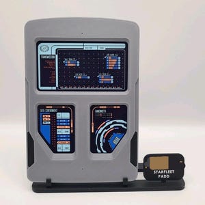 May include: A gray rectangular Starfleet PADD display stand featuring a large upper screen with transmission data and two lower screens labeled Data Containment and Bandwidth. A small black sign attached to the base reads STARFLEET PADD.