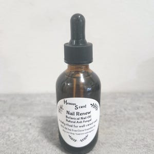 May include: A brown glass bottle with a black dropper top. The bottle has a white label with the text "Heaven Scent Nail Renew Botanical Nail Oil Natural Anti Fungal". The product is for nail care.