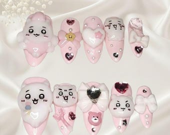 May include: A collection of ten artificial nails, each painted a pale pink and decorated with 3D elements. Designs feature cartoon characters, bows, hearts, and rhinestones. The nails are displayed on a white, textured background.