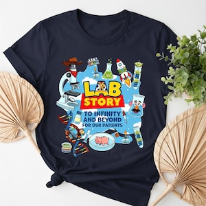 May include: Navy blue t-shirt with a colorful graphic featuring lab equipment, a rocket, and the text "Lab Story To Infinity and Beyond For Our Patients." The design includes a microscope, test tubes, and a pig.