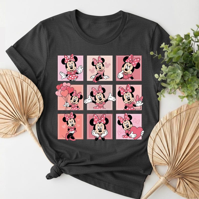 May include: Dark grey t-shirt with a grid of nine Minnie Mouse images. Each image is set against a pink background. Minnie Mouse is wearing a pink bow and dress in each image.