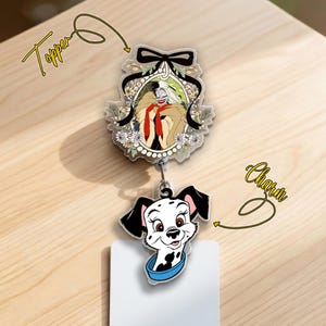 May include: A badge reel with a Cruella de Vil topper and a Dalmatian charm. The Cruella topper features a portrait of the character with a black bow and floral accents. The Dalmatian charm has a blue collar.