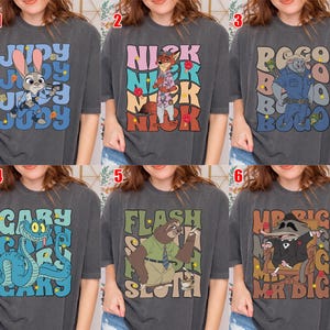 May include: Six dark gray t-shirts with cartoon character designs. The designs include Judy Hopps, Nick Wilde, Chief Bogo, Gary the Snake, Flash the Sloth, and Mr. Big. Each shirt has the character's name.