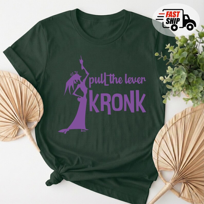 May include: Dark green t-shirt with a purple graphic of a character and the text "pull the lever KRONK". The shirt is made of a soft material and has a classic crew neck design. A fun and unique graphic tee.
