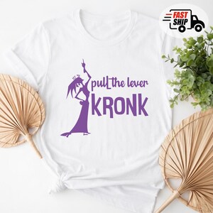 May include: White t-shirt featuring a purple silhouette of a character with the text "pull the lever KRONK". The design includes a crown and a long dress. A "Fast Ship" logo is in the upper right corner.