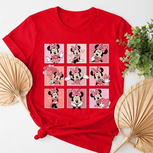 May include: A red t-shirt with a grid of nine Minnie Mouse illustrations. Each illustration is set against a pink or peach background. Minnie Mouse is wearing a polka dot bow and dress.